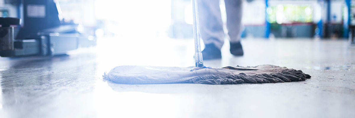 Mechanic using mop to clean concrete floor